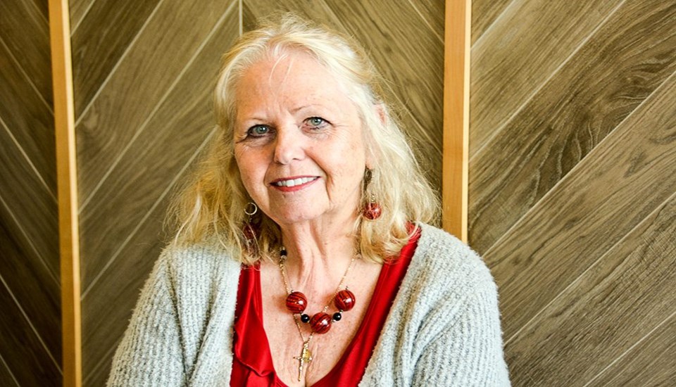 Irma Ruiter, smiling, wearing a red blouse and a cross necklace.